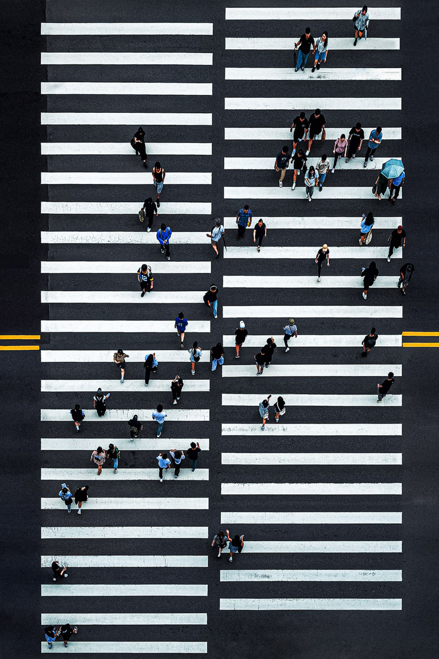 Ein Zebrastreifen von oben mit vielen Menschen, die die Straße überqueren