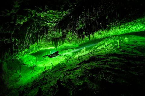 Taucher in Karsthöhle mit Tropfsteinen