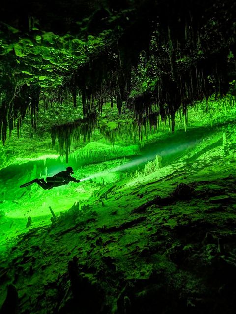 Taucher in Karsthöhle mit Tropfsteinen