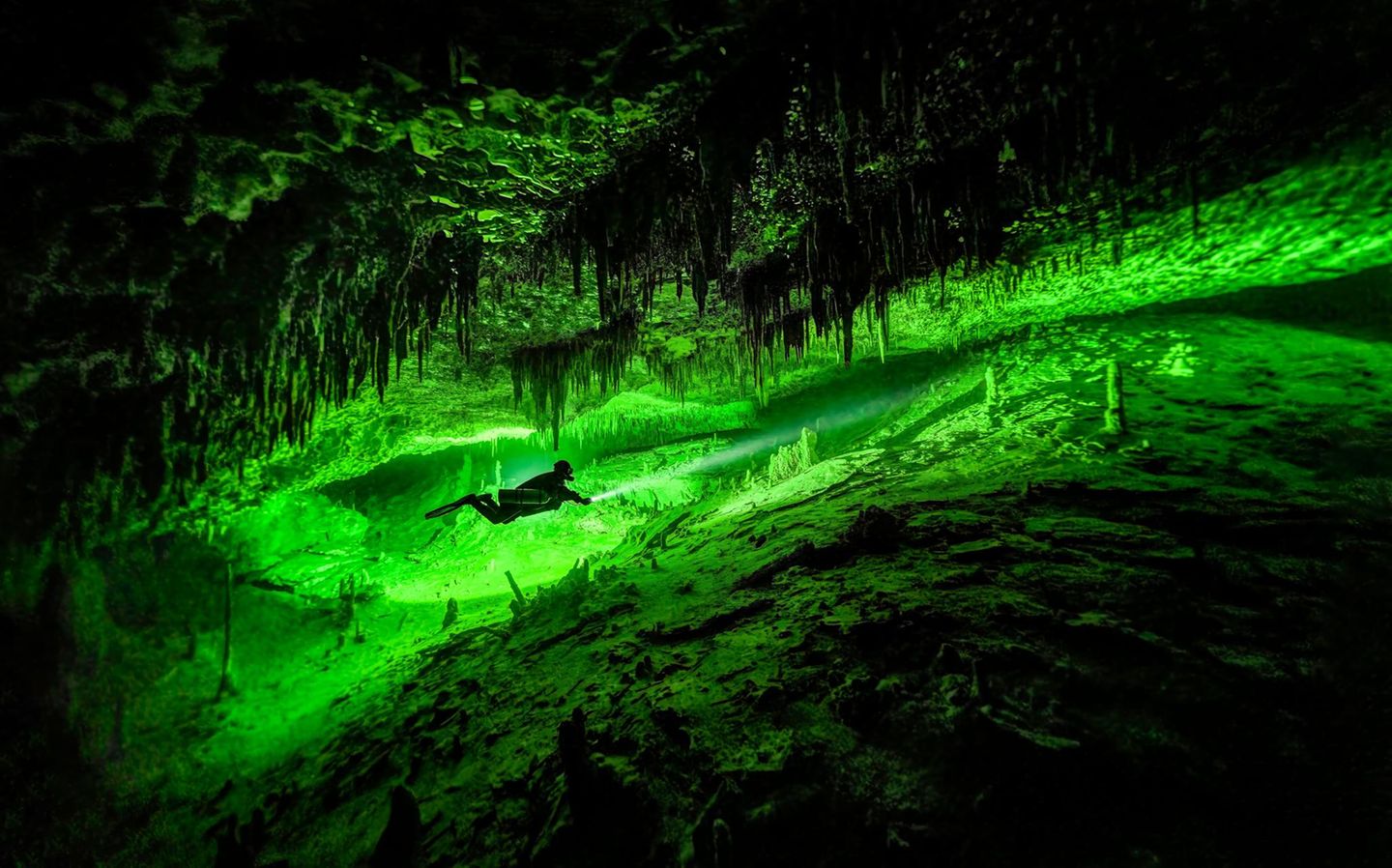 Taucher in Karsthöhle mit Tropfsteinen