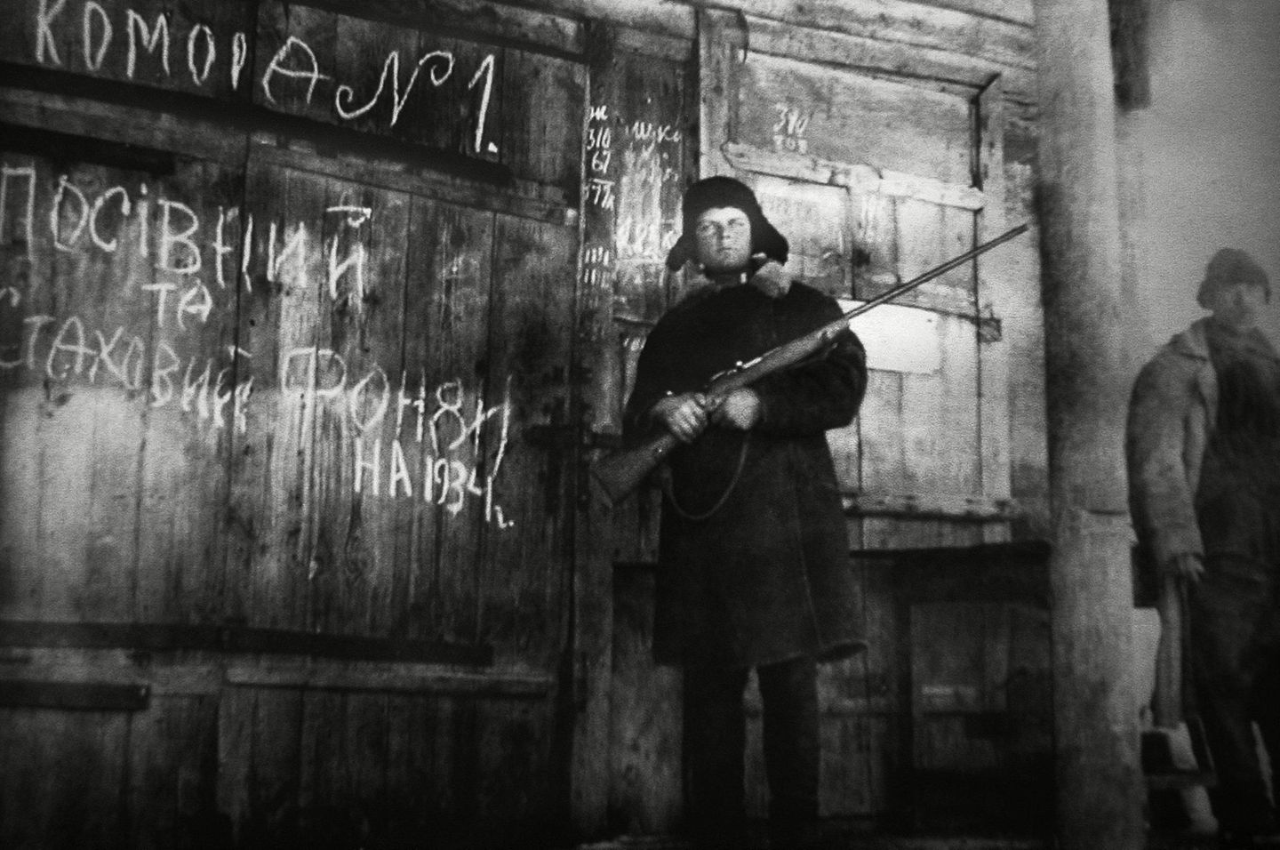 Mann mit Waffe vor Getreidelager