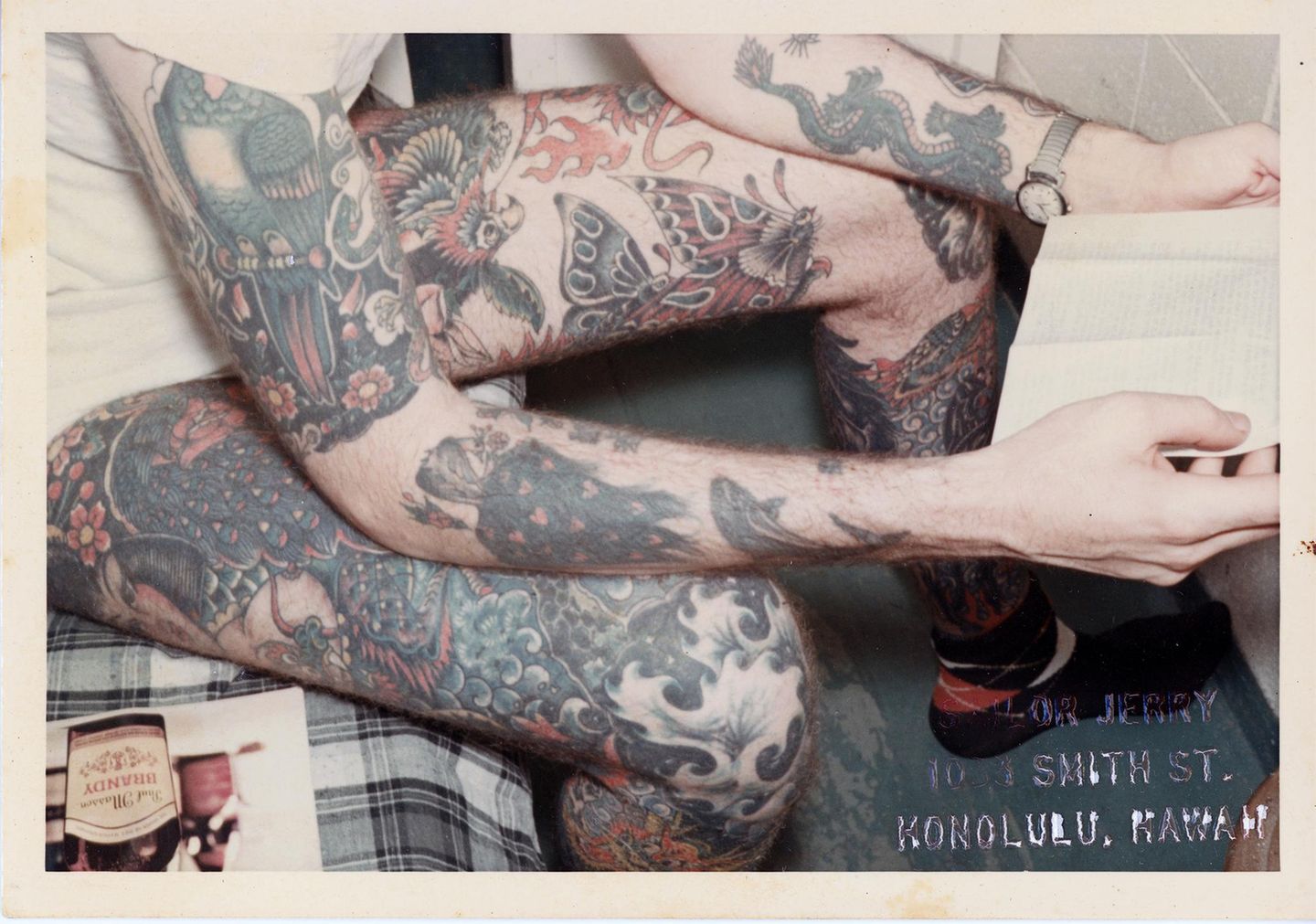 Mann mit tätowierten Beinen liest ein Buch