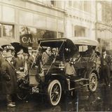 Eine Menschentraube mit Regenschirmen steht zwischen einem Auto und Gebäuden in New York