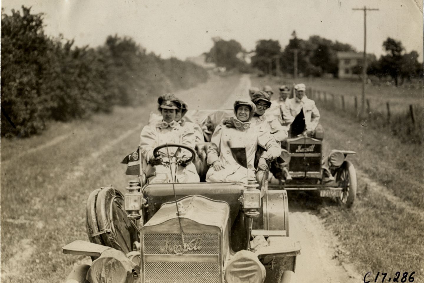 Zwei Wagen fahren 1909  über eine sandige Landstraße