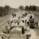 Zwei Wagen fahren 1909  über eine sandige Landstraße