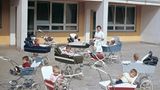Gruppe Kleinkinder in Kinderwägen und Betreuerin