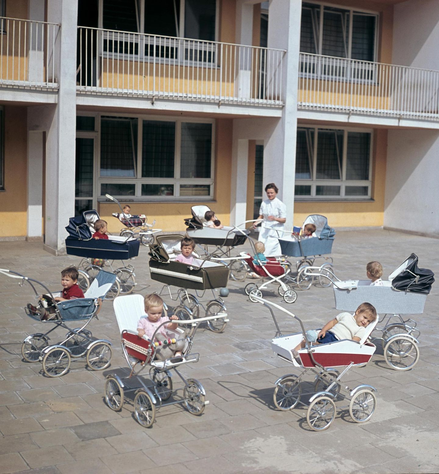 Gruppe Kleinkinder in Kinderwägen und Betreuerin