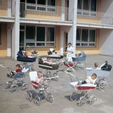 Gruppe Kleinkinder in Kinderwägen und Betreuerin