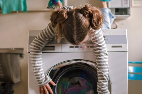 Mädchen liegt auf einer Waschmaschine