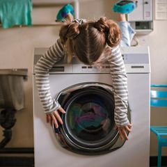 Mädchen liegt auf einer Waschmaschine