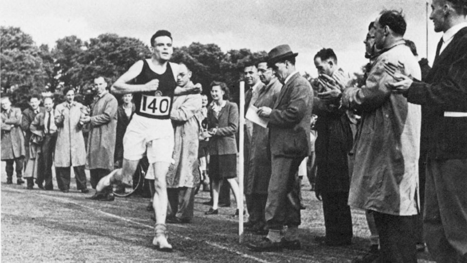 Alan Turing läuft durch eine Menge, auf seiner Brust die Startnummer 140