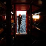 Hoch oben an den felsigen Hängen des Mont Dolent leuchtet das Bivouac du Dolent in kräftigem Orange – eine futuristisch anmutende Biwakschachtel, die selbst im weiten Weiß der Schneelandschaft unübersehbar bleibt. Sie bietet in absoluter Abgeschiedenheit eine einfache, aber gut geschützte Übernachtungsmöglichkeit. Das metallverkleidete Äußere widersteht Wind und Schnee, während das hölzerne innere mit Schlafplattformen und minimaler Ausstattung eine unerwartet warme Atmosphäre schafft. Dank eines Solarpanels gibt es sogar Strom für Beleuchtung und einen Wasserkocher – ein seltener Komfort in dieser rauen Umgebung.