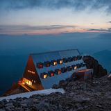 Auf 2.734 Metern thront diese klassische, aber modern gestaltete Hütte mitten im Naturpark Schlern-Rosengarten – und scheint mit einem warmen Leuchten zum Leben zu erwachen, sobald die Sonne hinter den Felstürmen der Rosengartengruppe versinkt. Das markante, dreieckige Gebäude schmiegt sich an den Stein und bietet einen unvergleichlichen Blick über Latemar, Ortler und bis zu den Alpen jenseits der Grenze.​ Einst erbaut vom Bergführer Giulio Gabrielli, verbindet das Rifugio Passo Santner mitten in den Dolomiten heute alpinistische Tradition und zeitloses Design.