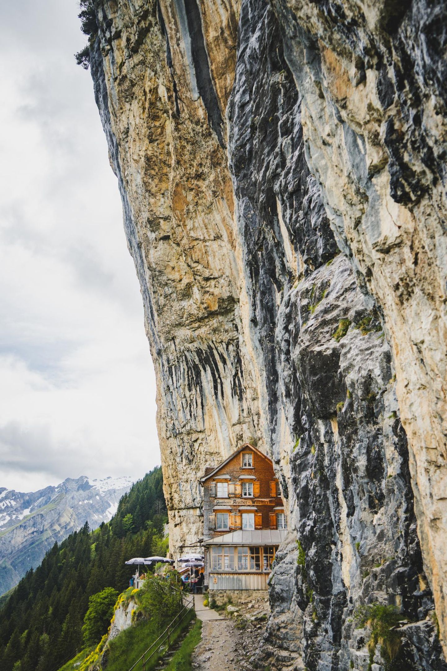 Berggasthaus Aescher in Weissbad, Schweiz Wie in einem Fantasy-Roman scheint das traditionelle Holzhaus auf 1.454 Metern direkt aus der senkrechten Felswand des Alpsteinmassivs zu wachsen: Dank der einzigartigen Lage am steilen Kalkstein zählt das Berggasthaus Aescher heute zu den berühmtesten Ausflugszielen der Region. Besucher erwartet neben einem sagenhaften Panoramablick auch herzliche Gastfreundschaft und eine märchenhafte Atmosphäre.