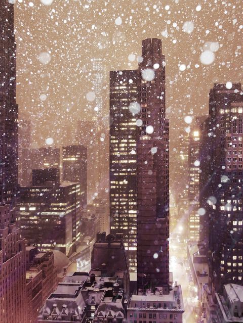 Hochhäuser einer Großstadt, die in rot-bräunlichen Farben scheinen, während Schnee fällt