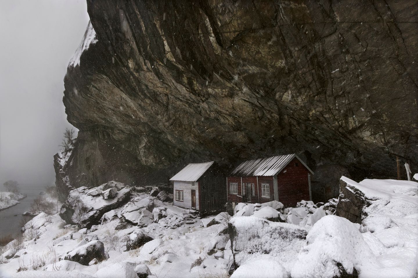 Zwei Hütten unter einer Felsformation im Schnee