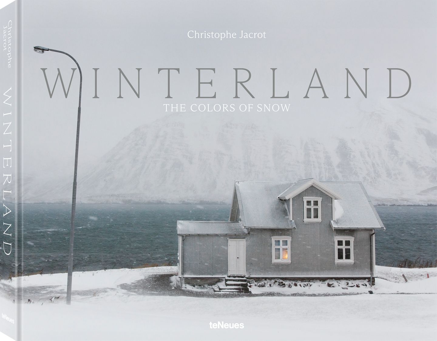 Buchtipp zur Fotostrecke Ein Haus steht vor einem Fjord und einem schneebedeckten Hügel auf Island