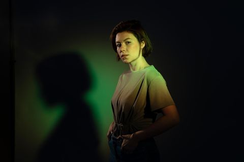 Confident woman standing with arms crossed against black background
