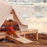 Frau sitzt an einem Zelt im Saqqaq Camp in Grönland