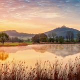 Spiegelnde Bäume, Hügel und Burg im See
