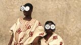 Zwei junge Menschen posieren vor einer rauen Wand, in reich bestickten Gewändern aus Aso Oke – jenem handgewebten Stoff aus Nigeria, der traditionell bei Zeremonien getragen wird. Ihre Gesichter sind größtenteils von futuristischen Brillen aus recycelten VHS-Kassetten verdeckt – eine witzige und prägnante Metapher für die Verwandlung veralteter Technik in ein neues Ritualobjekt und Werkzeug des kulturellen Ausdrucks.