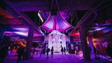 Besucherinnen und Besucher in einer Ausstellungshalle in violettem Licht