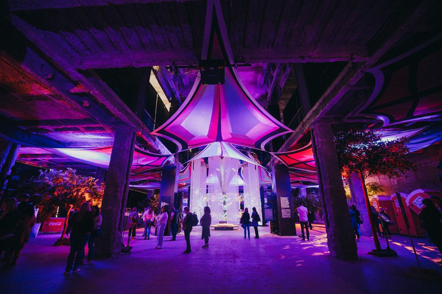 Besucherinnen und Besucher in einer Ausstellungshalle in violettem Licht