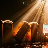 Dixie-Toiletten werden von einem Scheinwerfer durch einen Baum angestrahlt