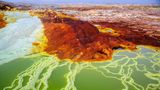 Die rot-braune Dallol Vulkanlandschaft, welche von weißen bis blauen Naturbecken und Salztürmen durchsäht ist