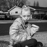 Ein Kind sitzt auf der Straße und hält ein Sandwich in der Hand