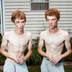 Zwillinge mit roten Haareen stehen oberkörperfrei nebeneinander