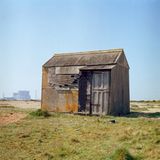 Eine kleine Holzhuette, welche alleine auf einer Wiese steht