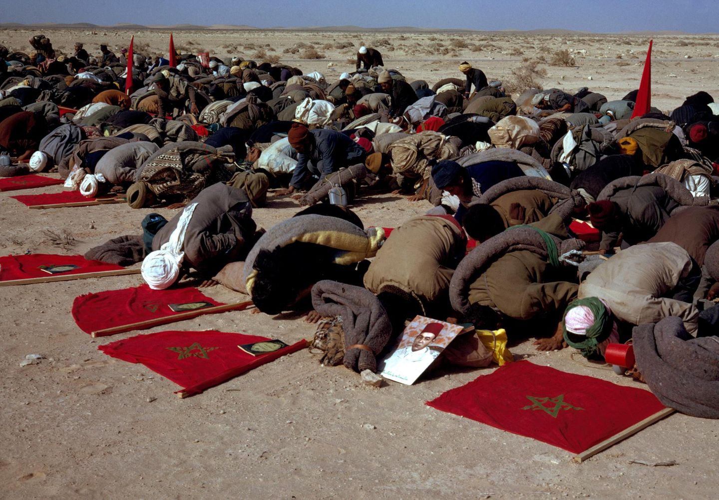 Menschen knien im Sand nieder und beten