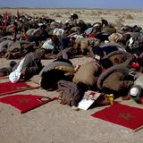 Menschen knien im Sand nieder und beten