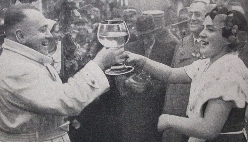 Ein Mann bekommt ein sehr großes gefülltes Weinglas von einer Frau gereicht.