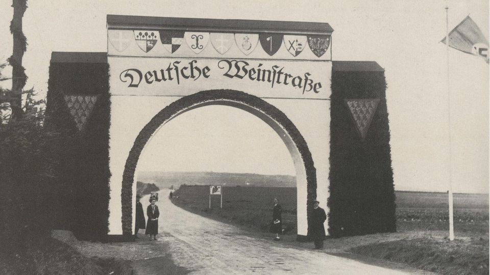 Weißer Torbogen über einer Straße mit der Aufschrift "Deutsche Weinstraße"