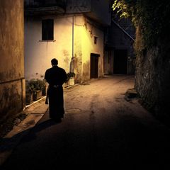 Ein Priester läuft durch eine beleuchtete Gasse