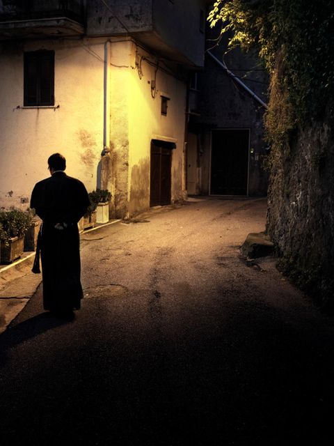 Ein Priester läuft durch eine beleuchtete Gasse