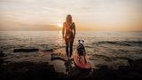 Vertrauen und Abenteuerlust verbinden dieses Duo: Das stimmungsvolle Bild von Hund, Frau und Surfboard in der sanften Brandung wurde in der Kategorie "Hunde & Menschen" besonders hervorgehoben. Eingereicht hat es die Österreicherin Petra Nestelbacher.