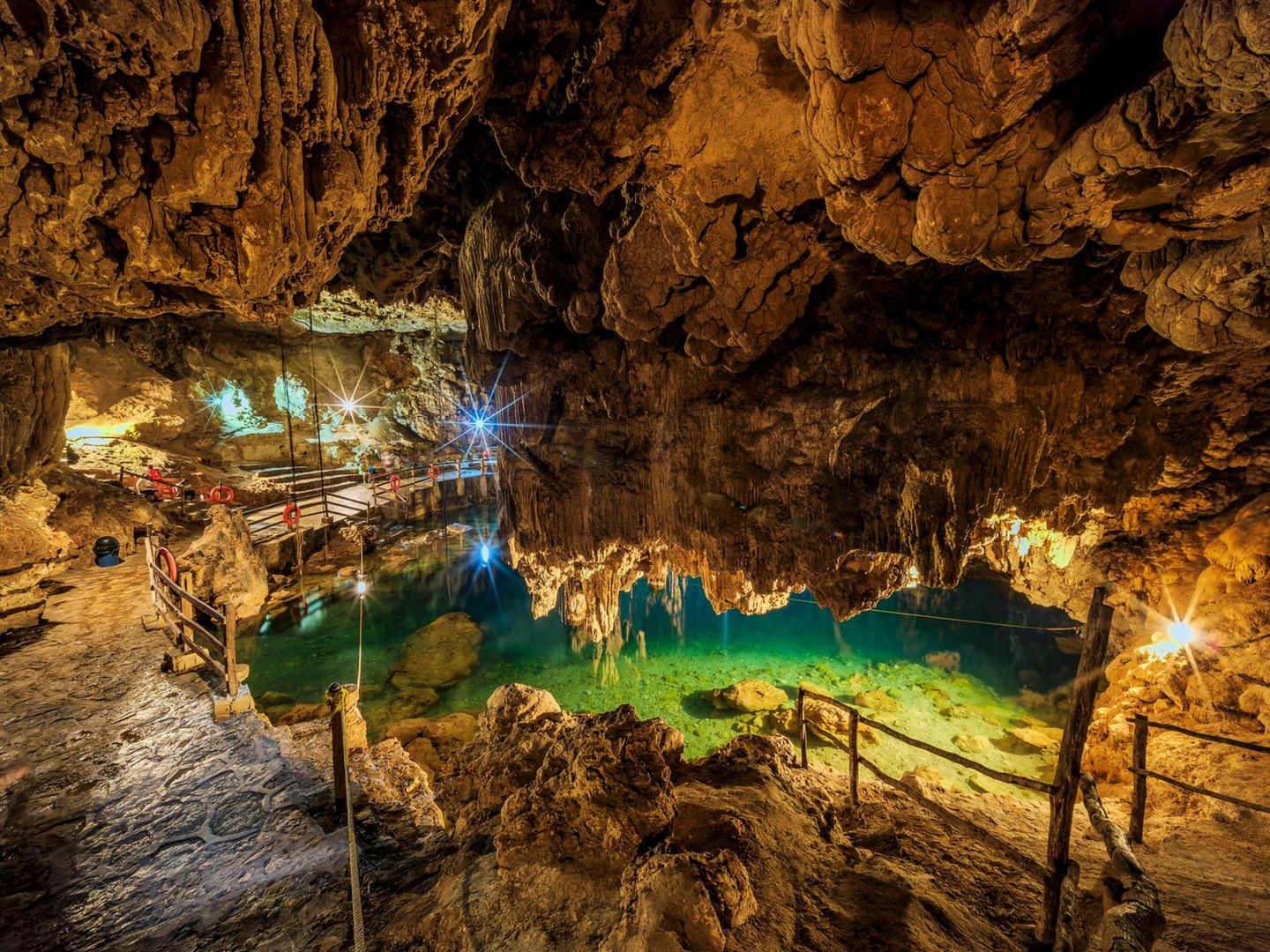 Der Blick in die beleutete Xkeken Cenote, in der sich türkisenes Wasser befindet