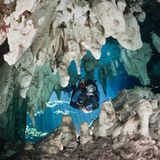 Eine tauchende Person taucht durch einen Durchgang in der Gran Cenote