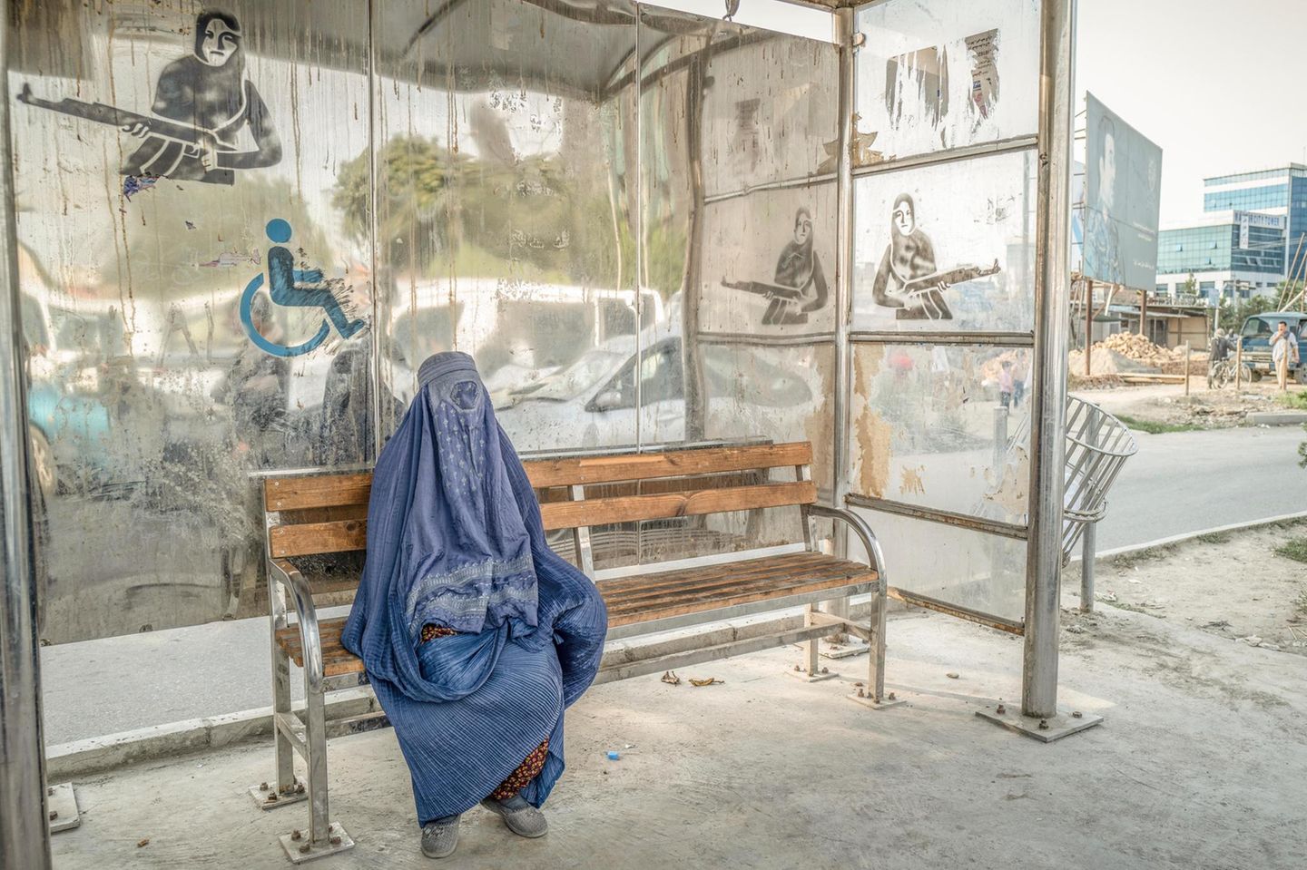 Eine Frau wartet 2020 an einer Kabuler Bushaltestelle