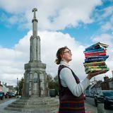 Frau, die einen Stapel Bücher in Wigtown, Schottland, hält