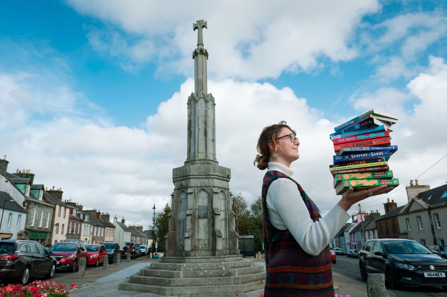 Frau, die einen Stapel Bücher in Wigtown, Schottland, hält