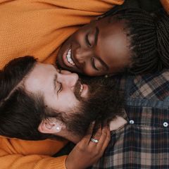 Ein Paar liegt Kopf an Kopf and lächelt einander an