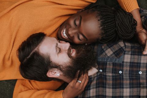 Ein Paar liegt Kopf an Kopf and lächelt einander an