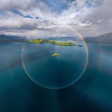 Ein runder Regenbogen erhebt sich über einen chinesischen Gebirgssee