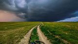 Bis zum Ende des Horizonts Ein Sturm zieht über einem Feldweg auf, auf dem ein Fahrrad liegt