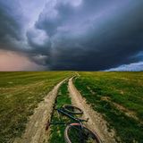 Ein Sturm zieht über einem Feldweg auf, auf dem ein Fahrrad liegt