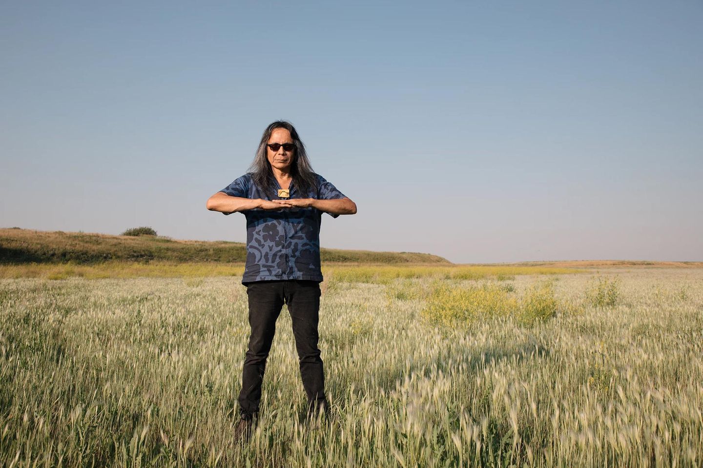Ein Mann steht mit aufeinandergelegten Handflächen in einem Feld